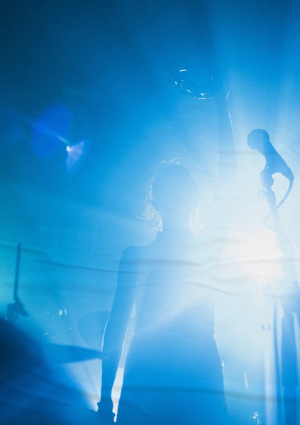 Femme sur scène à contre-jour, lumière bleue, micro à l'avant-plan