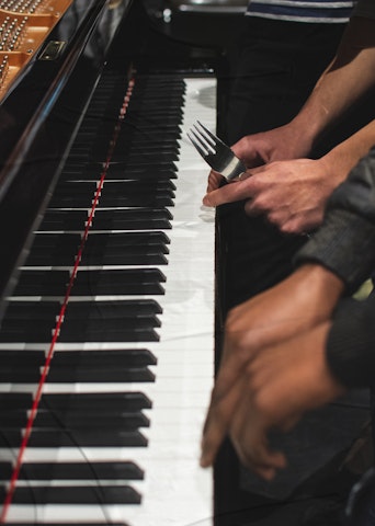 Clavier de piano, quatre mains dont une tient une fourchette