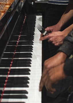 Clavier de piano, quatre mains dont une tient une fourchette